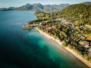 Vista aérea de la costa de Koh Chang, Tailandia, con playa de arena blanca, aguas turquesas y vegetación tropical.