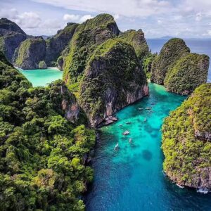 Playa con aguas cristalinas rodeada de acantilados verdes en las Islas Phi Phi, Tailandia, mostrando un paisaje tropical impresionante.