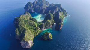 Vista aérea de Maya Bay, una bahía rodeada de acantilados verdes y aguas turquesas en Tailandia.