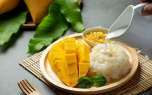Mango sticky rice, postre tradicional de la gastronomía de Tailandia, arroz glutinoso con leche de coco y mango maduro.