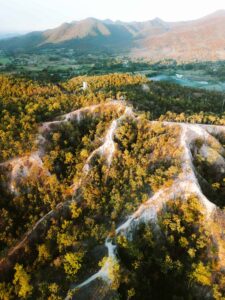 Vista aérea del Pai Canyon en el norte de Tailandia durante el atardecer, con senderos estrechos y formaciones rocosas iluminadas por tonos dorados.